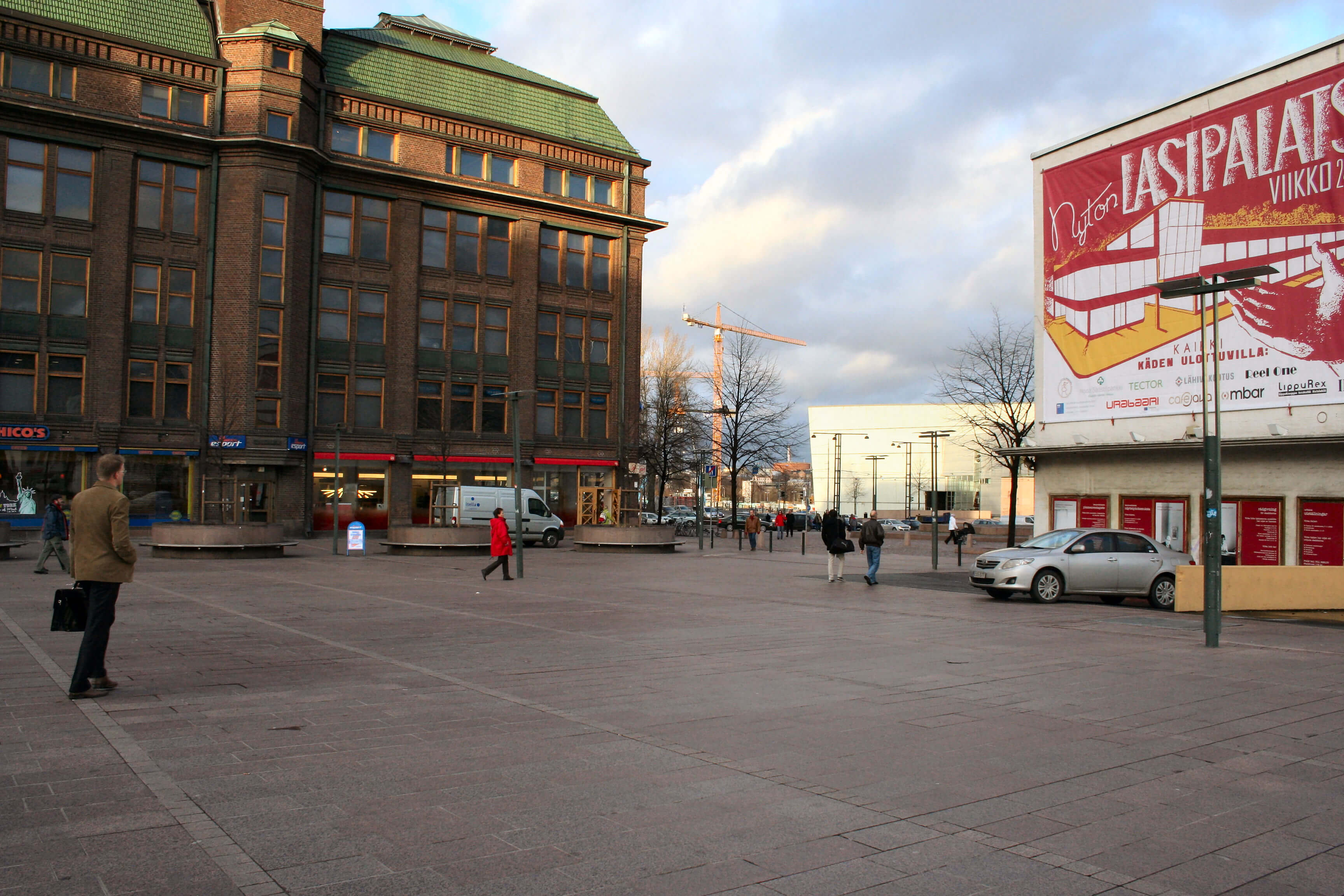 ihmisiä kävelemässä aukiolla kaupungissä