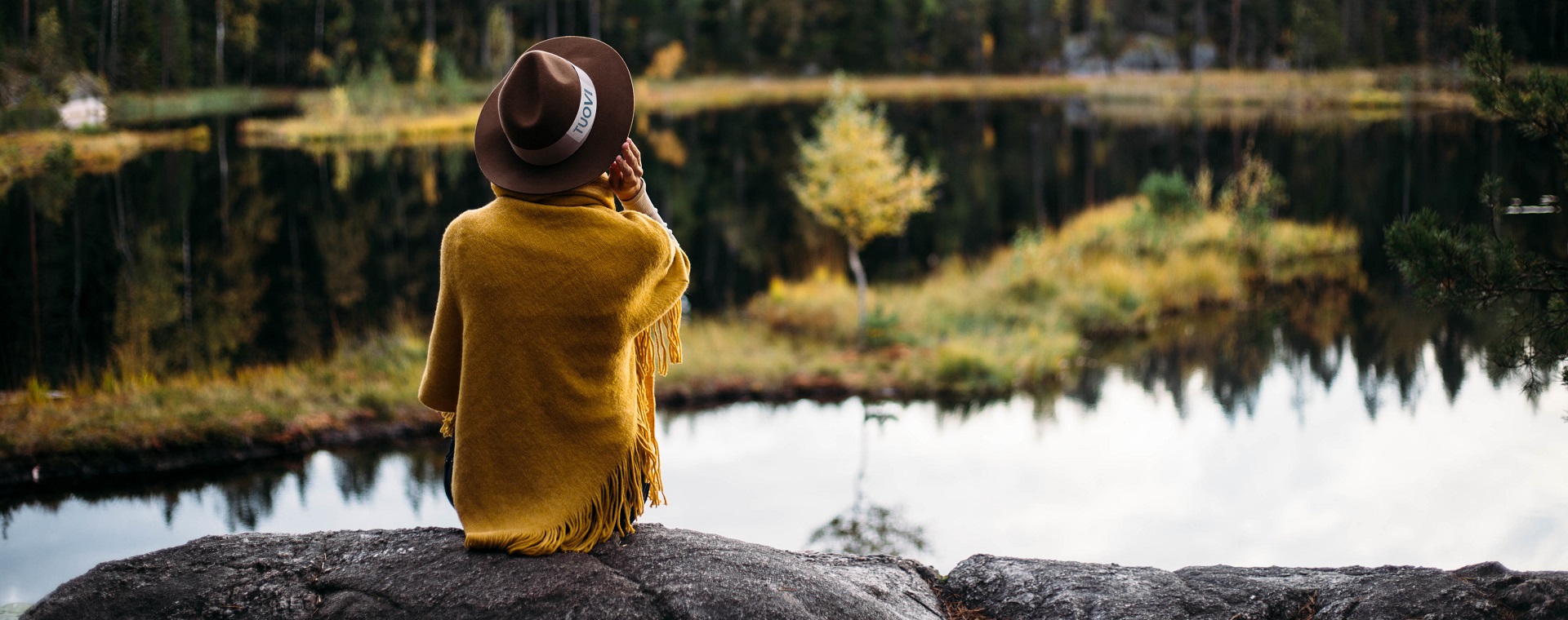 Girl sitting on a rock watching the lake