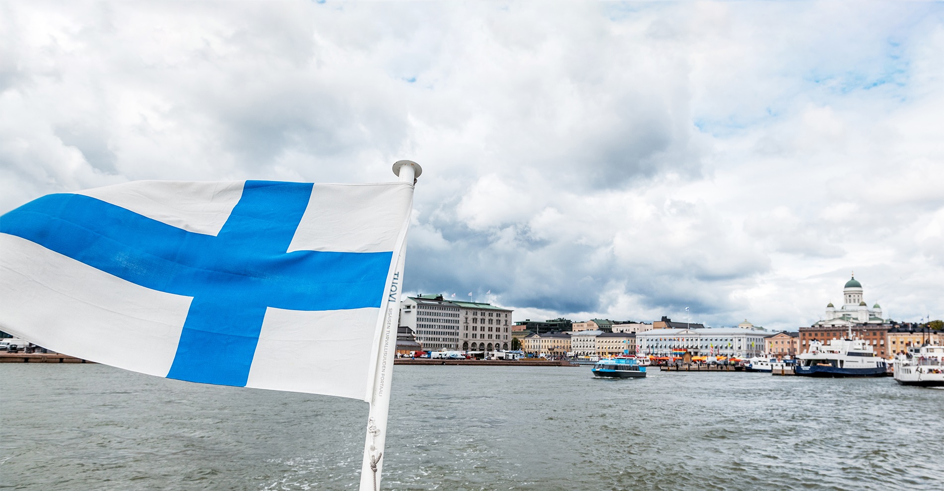 Suomen lippu veneen perämisessä, Helsinki taustalla.
